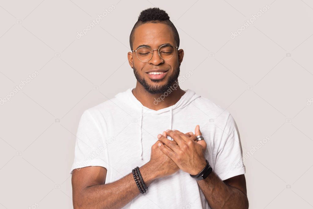 Grateful black man hold hands at chest feeling thankful