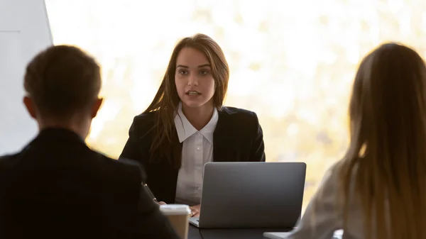 Les hommes d'affaires qui négocient dans une salle de conférence se concentrent sur une jeune femme d'affaires confiante — Photo