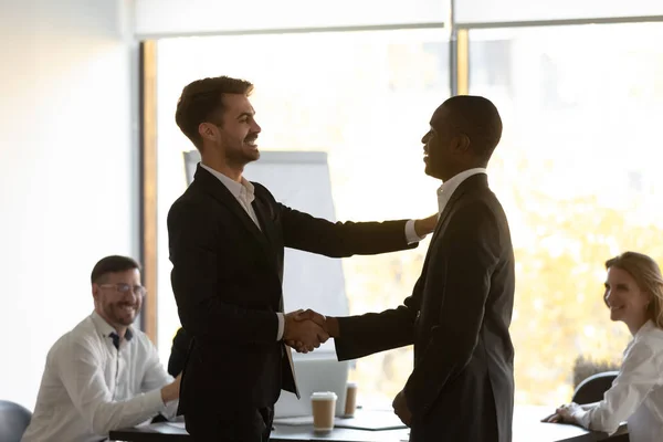 Boss praises handshaking African member during briefing in office boardroom — Stock Photo, Image