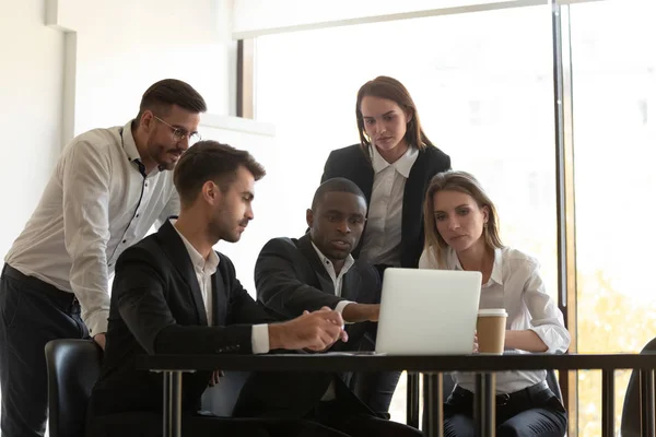 Líder de equipo africano mostrando ayuda de aplicación a compañeros de trabajo usando computadora portátil — Foto de Stock