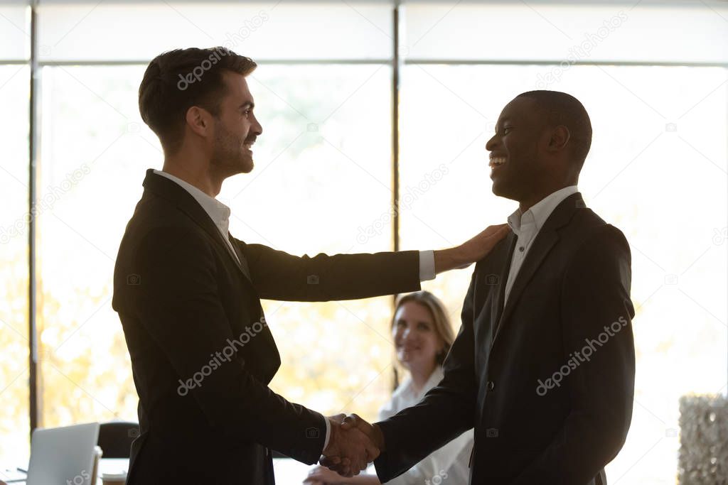 Boss handshaking with african team leader thanking for successful work