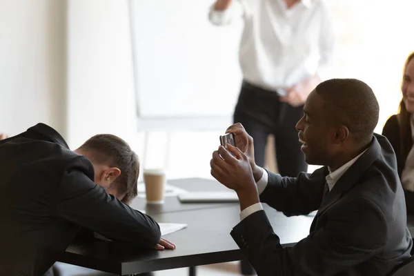 Empleado durmiendo durante sesión informativa colega africano toma fotos de él — Foto de Stock