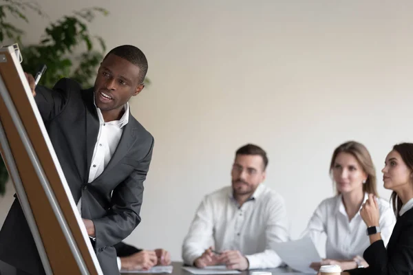 African group leader using flipchart writing information for corporate staff — Stock Photo, Image