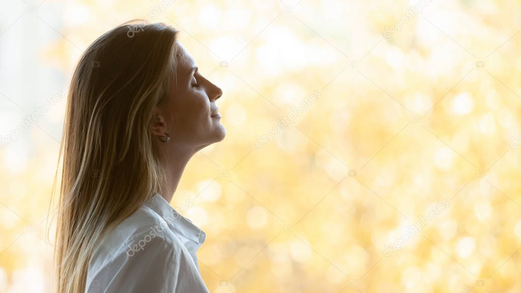 Businesswoman breathing fresh air standing near window with autumn scenery