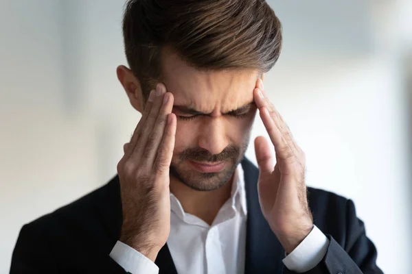 Hombre de negocios fruncir el ceño cara ojos cerrados toca las sienes reduce el dolor de migraña — Foto de Stock