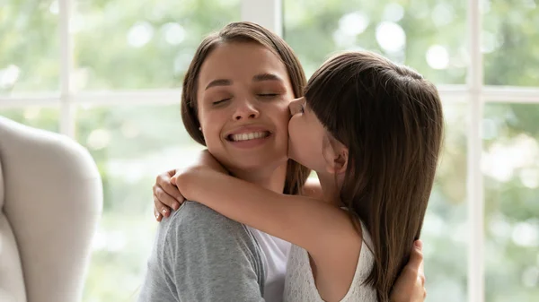 Liefdevolle kleine meisje knuffel en kus jonge moeder — Stockfoto