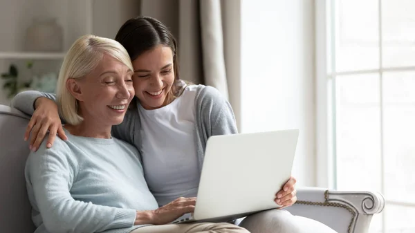 Счастливая пожилая мать и взрослая дочь вместе пользуются ноутбуком — стоковое фото