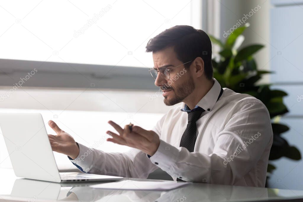 Indignant businessman looks at pc screen having problems with laptop