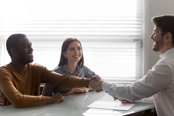 Bank worker congratulating couple taking loan signing family mortgage contract