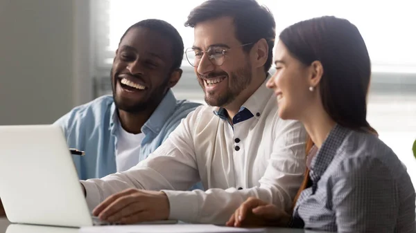 Three multi-ethnic colleagues watching funny prank videos at workplace — Stock Photo, Image