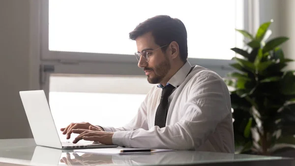 Zakenman gezeten aan een bureau lanceren van online opstarten project met behulp van laptop — Stockfoto