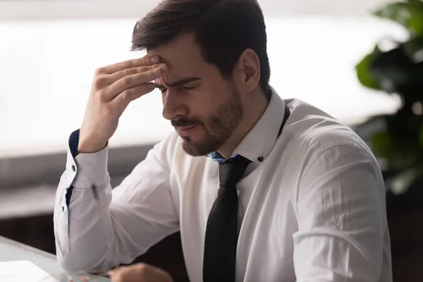 Empresario con dolor de cabeza en el lugar de trabajo sintiéndose cansado y con exceso de trabajo —  Fotos de Stock
