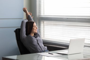 İşyerindeki sandalyeye yaslanan iş kadını işini bitirince tatmin oluyor.