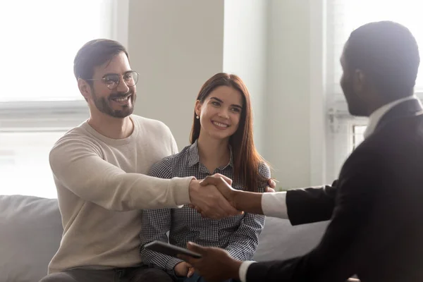 Afrikanischer Immobilienmakler und Kunden geben sich sitzend die Hand — Stockfoto