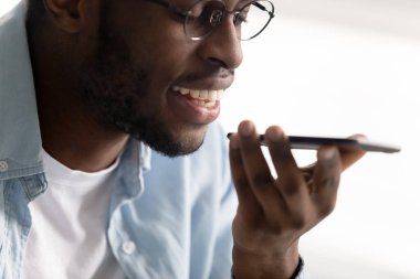 Sanal dijital ses asistanı kullanarak akıllı telefon tutan Afrikalı adam.