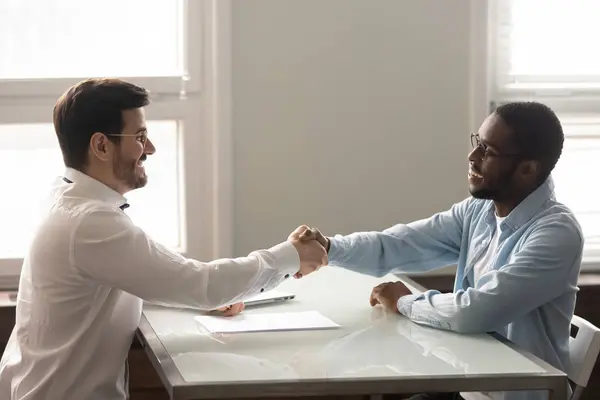 Empresarios africanos y caucásicos se dan la mano y comienzan a reunirse — Foto de Stock