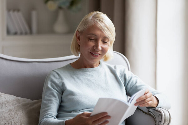 Middle-aged mature woman reading interesting book at home