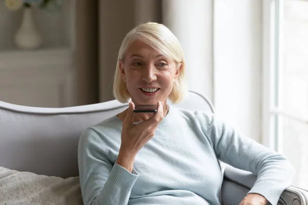 Женщина средних лет разговаривает по мобильному телефону с помощью громкоговорителя — стоковое фото