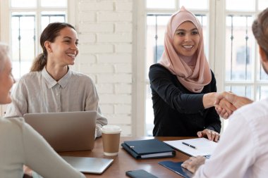 Toplantıda gülümseyen Arap iş kadını el sıkışması iş ortağı