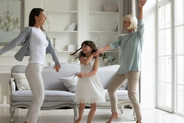 Nadšené tři generace žen tančících v jasném obývacím pokoji — Stock fotografie