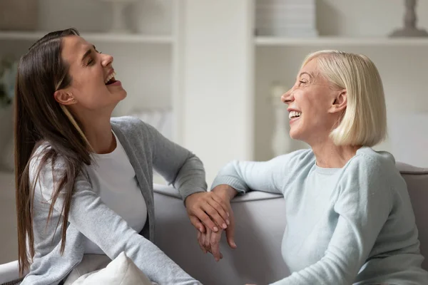 Веселая старшая мама и взрослая дочь смеются, разговаривая дома. — стоковое фото