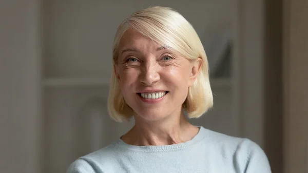 Портрет улыбающейся женщины средних лет, позирующей дома — стоковое фото