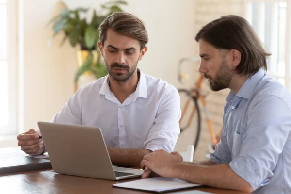 Confident male colleagues cooperate at laptop at meeting — Stock Photo, Image