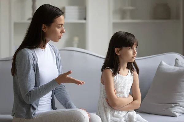 Young mom lecture sad little daughter at home
