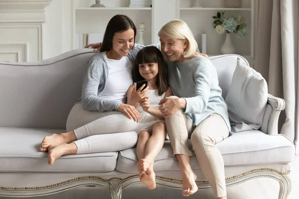 Šťastné tři generace žen relaxovat doma pomocí mobilu — Stock fotografie
