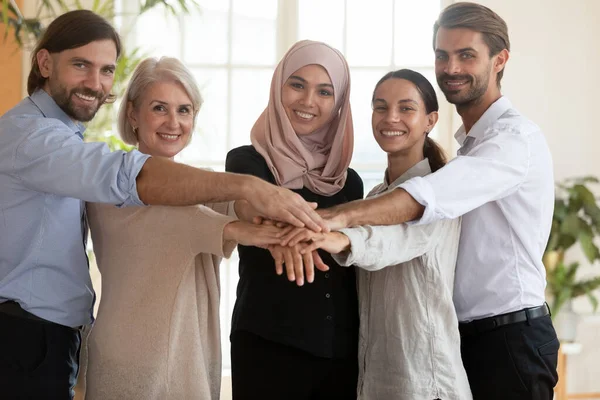 Portrait of smiling diverse employees stack hands together
