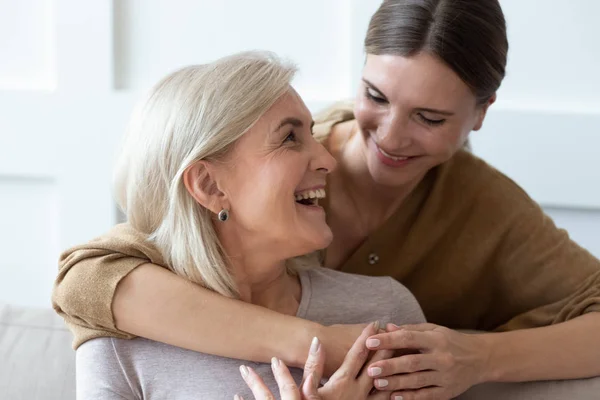 Adulto figlia abbracciare anziano mamma mostrando amore e cura — Foto Stock