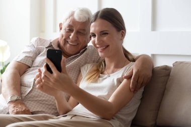 Gülümseyen olgun baba ve yetişkin kız birlikte selfie çekiyorlar.