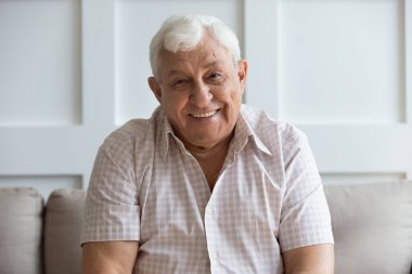 Kanepede rahatlarken gülümseyen olgun adamın portresi.