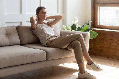 Sakin bir milenyum kadını kanepede gözleri kapalı dinleniyor.