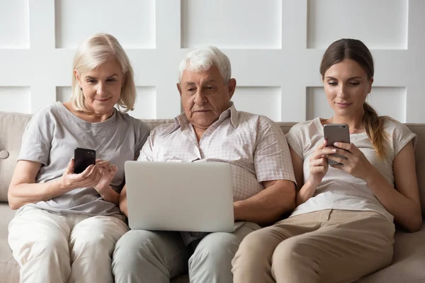 Família adulta moderna sentar no sofá usando gadgets juntos — Fotografia de Stock