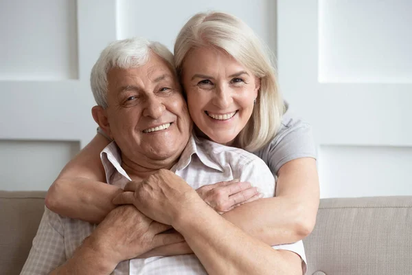 Liefdevolle senior man en vrouw knuffelen kijken naar camera — Stockfoto