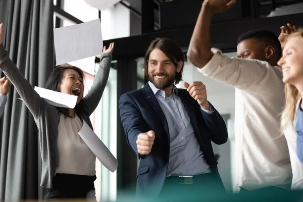 Diversos compañeros de trabajo emocionados celebrando el éxito, lanzando papeles, regocijando logro — Foto de Stock