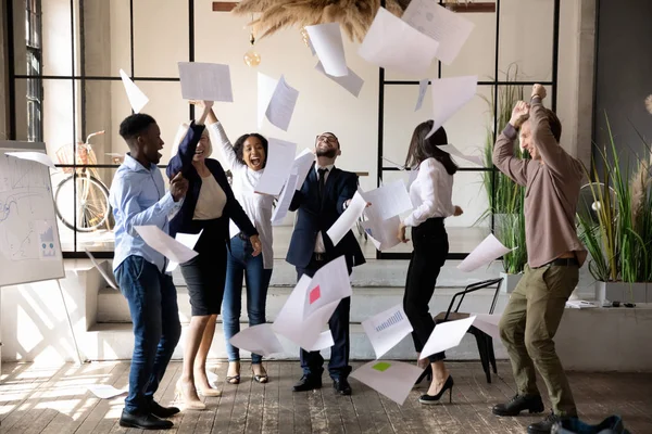 Mångsidig personal kastar papper upp firar företagets framgång känns överlycklig — Stockfoto