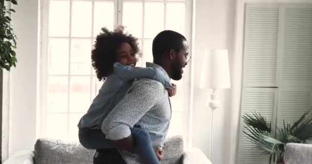 African dad carrying kid daughter giving piggyback ride at home — Stock Video