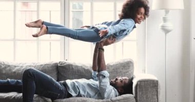 Happy cute afro american girl playing plane with young father