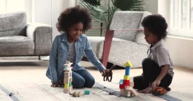 Happy african children playing toys sit on floor at home