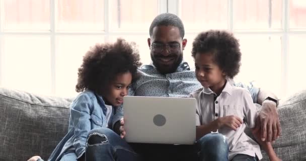 Smiling african dad and kids enjoying using laptop at home — 비디오