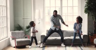 African dad dancing having fun with kids in living room