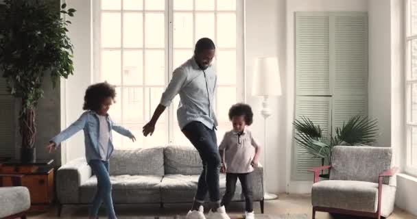 Funny african children dance with father in living room interior — Stockvideo