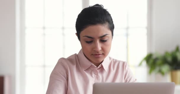 Focused indian businesswoman using laptop thinking doing research in office — Stockvideo