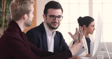 Friendly male coworkers having conversation working together on pc