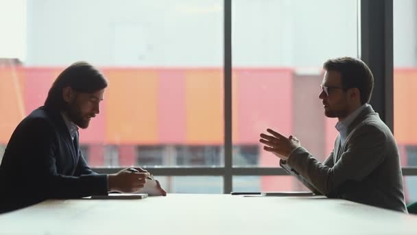 Hombres de negocios serios discutiendo las condiciones de asociación en la oficina moderna . — Vídeo de stock