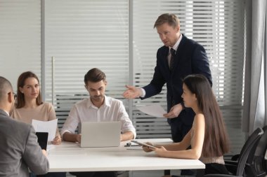 Erkek Ceo ekip liderleri iş arkadaşlarıyla evrak işlerini tartışıyor.