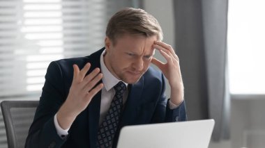 Dizüstü bilgisayar sorunları yüzünden kafası karışmış erkek çalışan