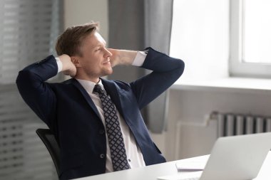 Düşünceli erkek çalışan. Sandalyede rahatlayıp iş yerinde hayal kuruyor.